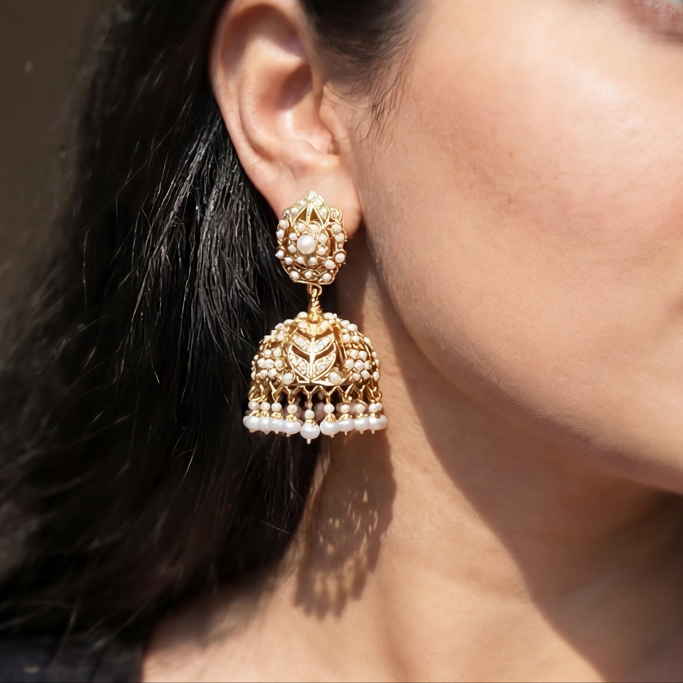 Woman wearing gold earrings with a neutral background