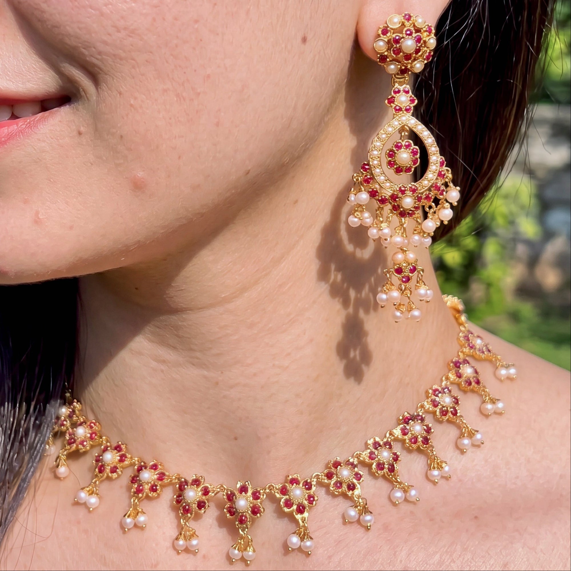 Close-up of a pakistani woman wearing a detailed necklace and earrings with a blurred natural background