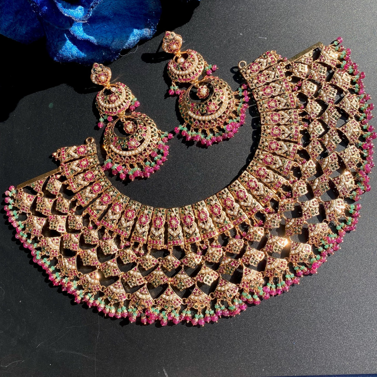 NS 517 pink and green jaal bib necklace with pearl floral panels, bead fringe and matching double chandbali earrings on a black background.