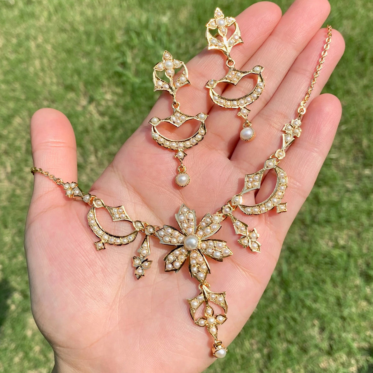 vintage pearl necklace set held on hand in bright natural sunlight in a garden 