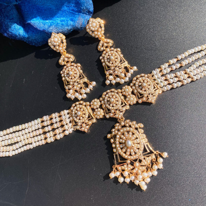 NS 516 angled detail of the pearl choker, central floral pendant and matching earrings on a dark surface